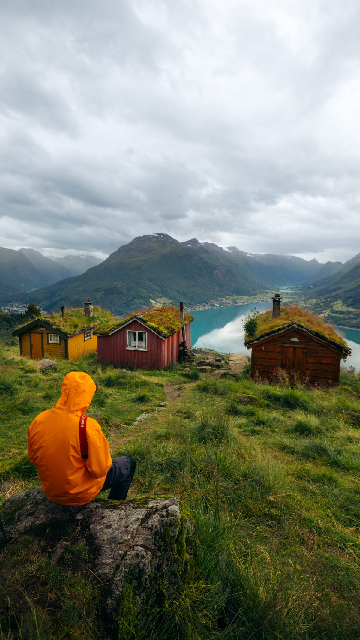 Sitting above turf-roofed cabins looking out over a fjord