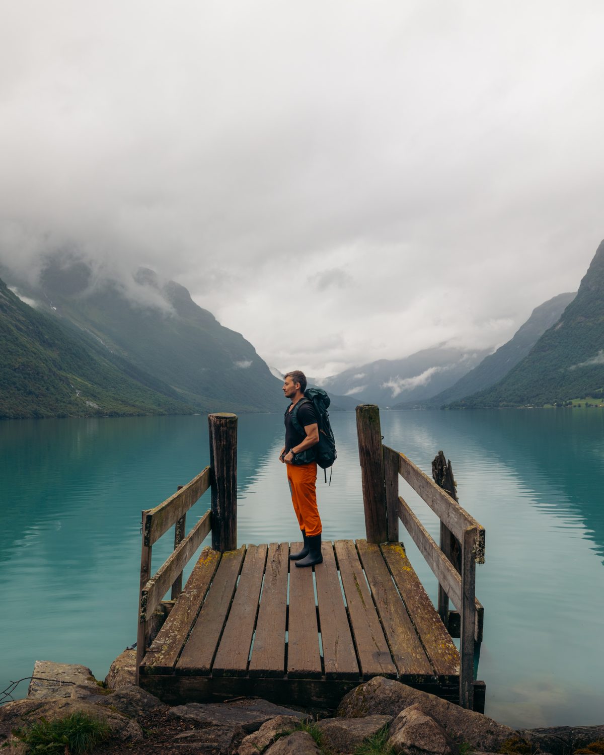 Standing on a wooden jetty on a still glacial lake ringed by mountains